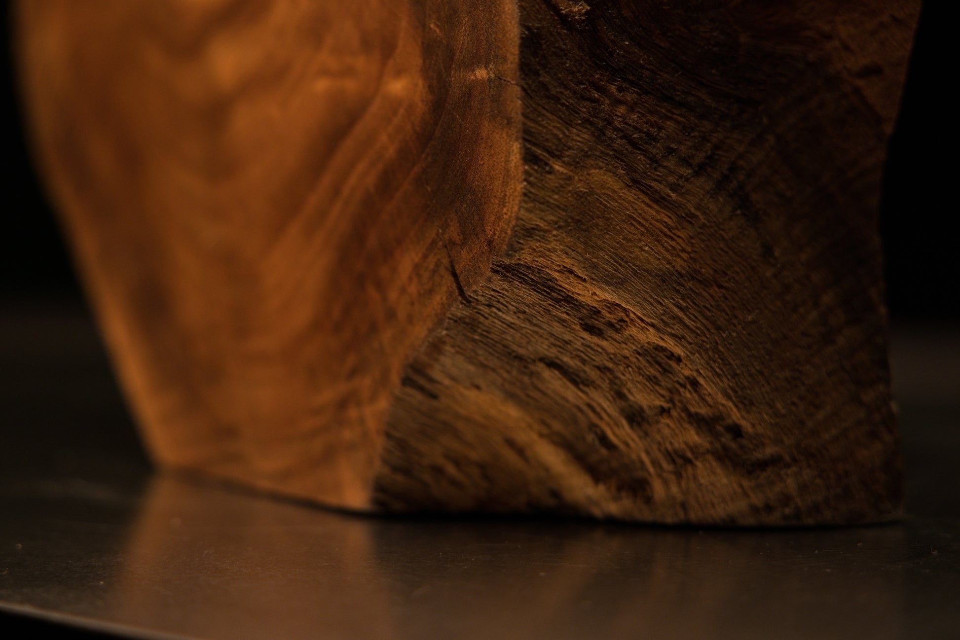 Profile view of a cylindrical wooden extension reaching out from a dark inner shadow within the sculpted display.   