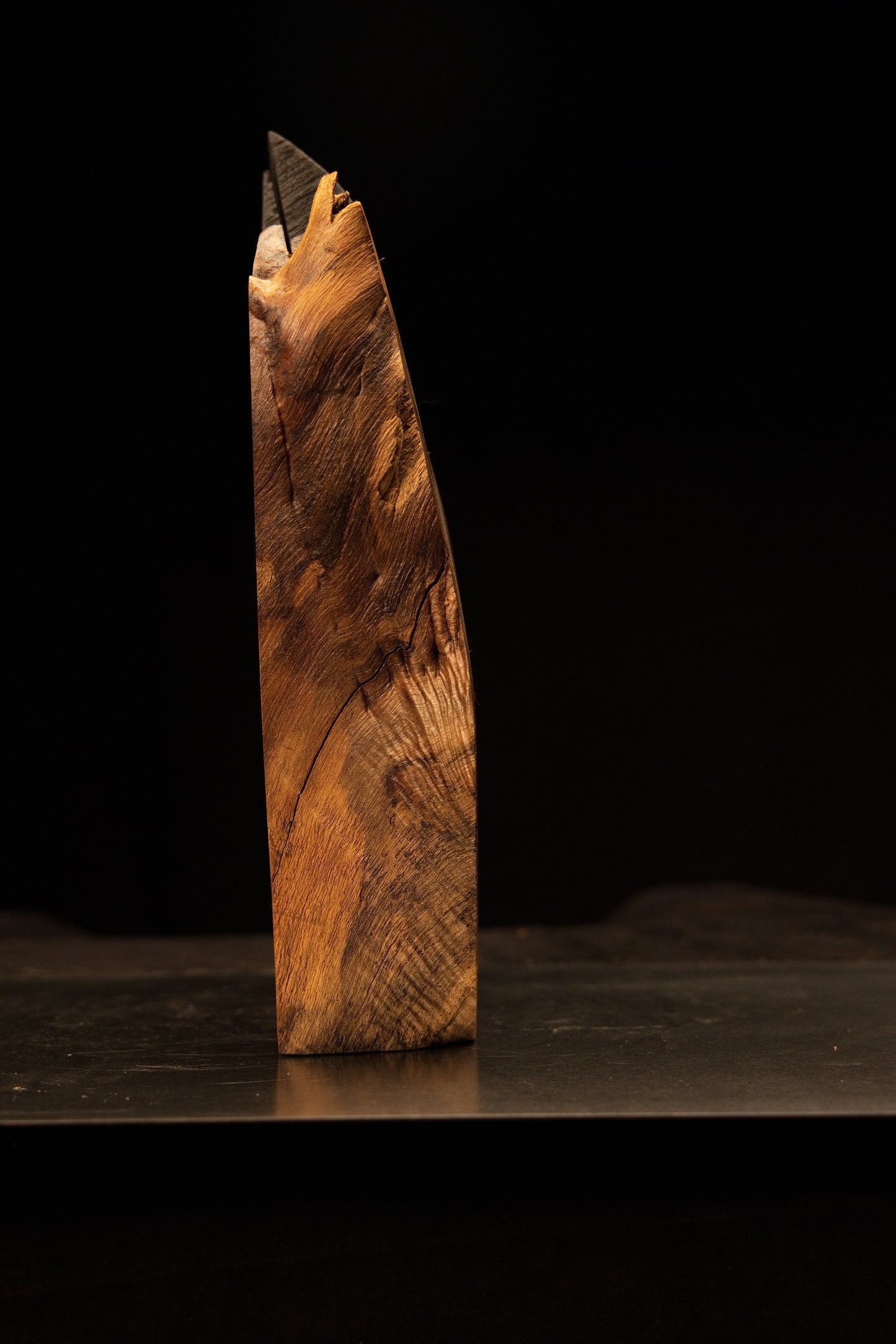 Close-up tracking the sweeping golden grain lines right along the flat foundation edge of the luxury wooden monolith.   