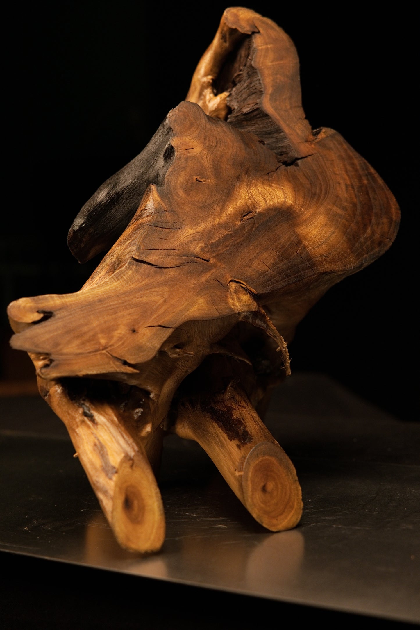 Angled profile of a relic-grade wood sculpture featuring protruding root bases and a deep charred internal organic cavity.   