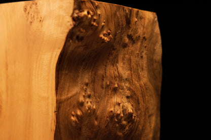 Macro study of sweeping golden grain lines curving gracefully around dense burl eyes on a perfectly stabilized structural monolith.   