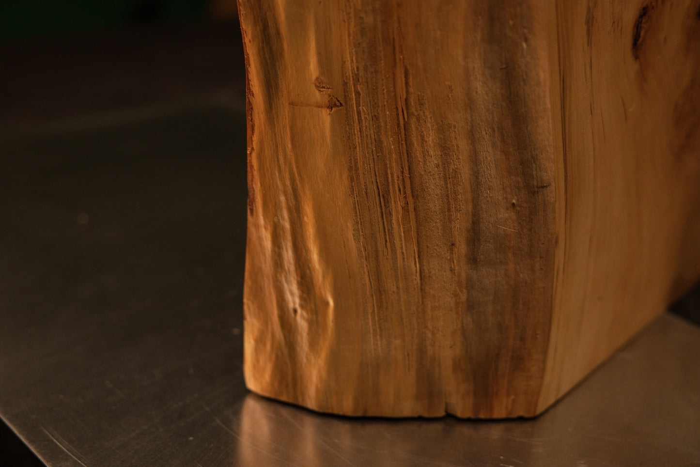 Detailed lower corner framing showing dense vertical wood fibers uniting seamlessly with a precise flat baseline foundation cut.   