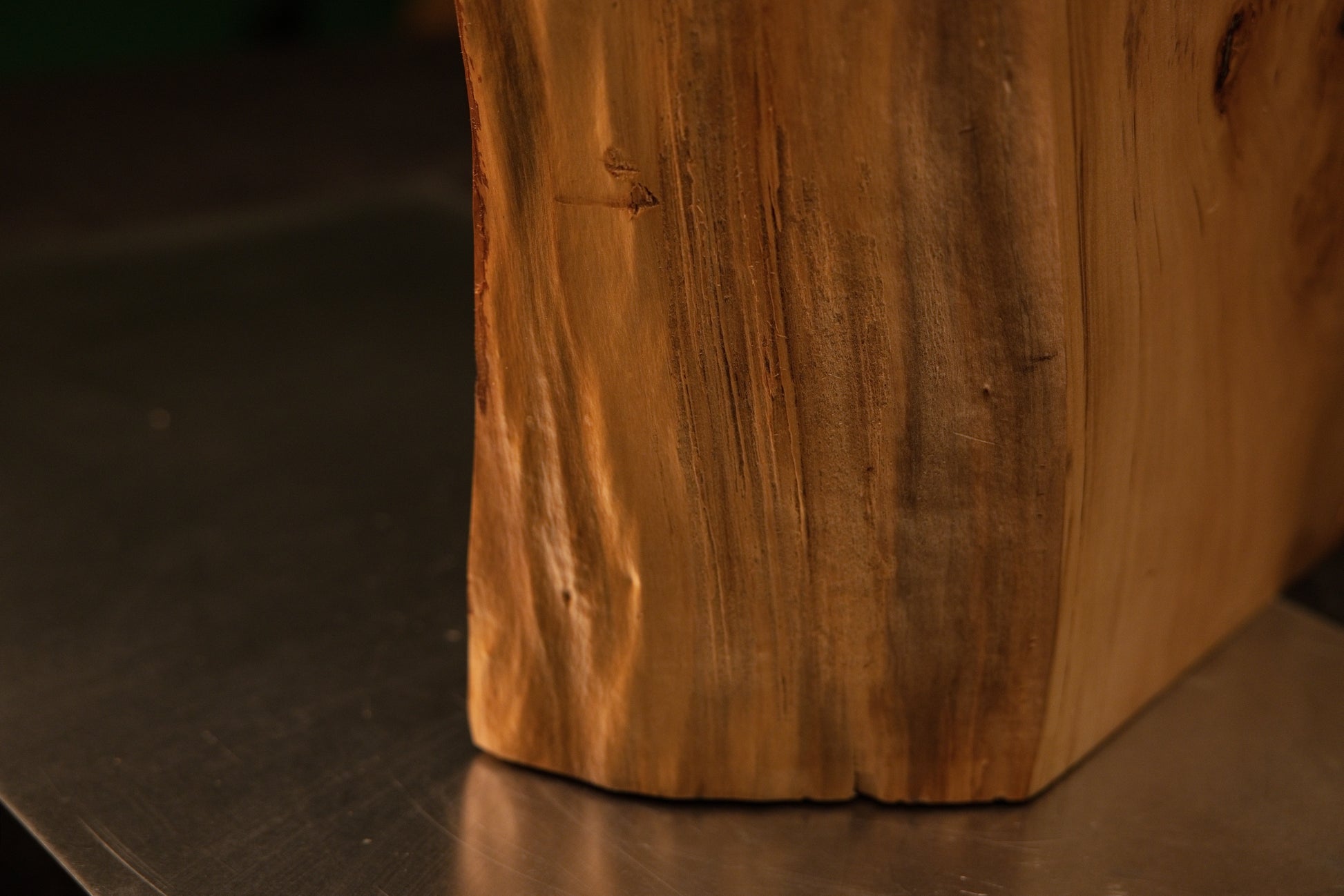 Detailed lower corner framing showing dense vertical wood fibers uniting seamlessly with a precise flat baseline foundation cut.   