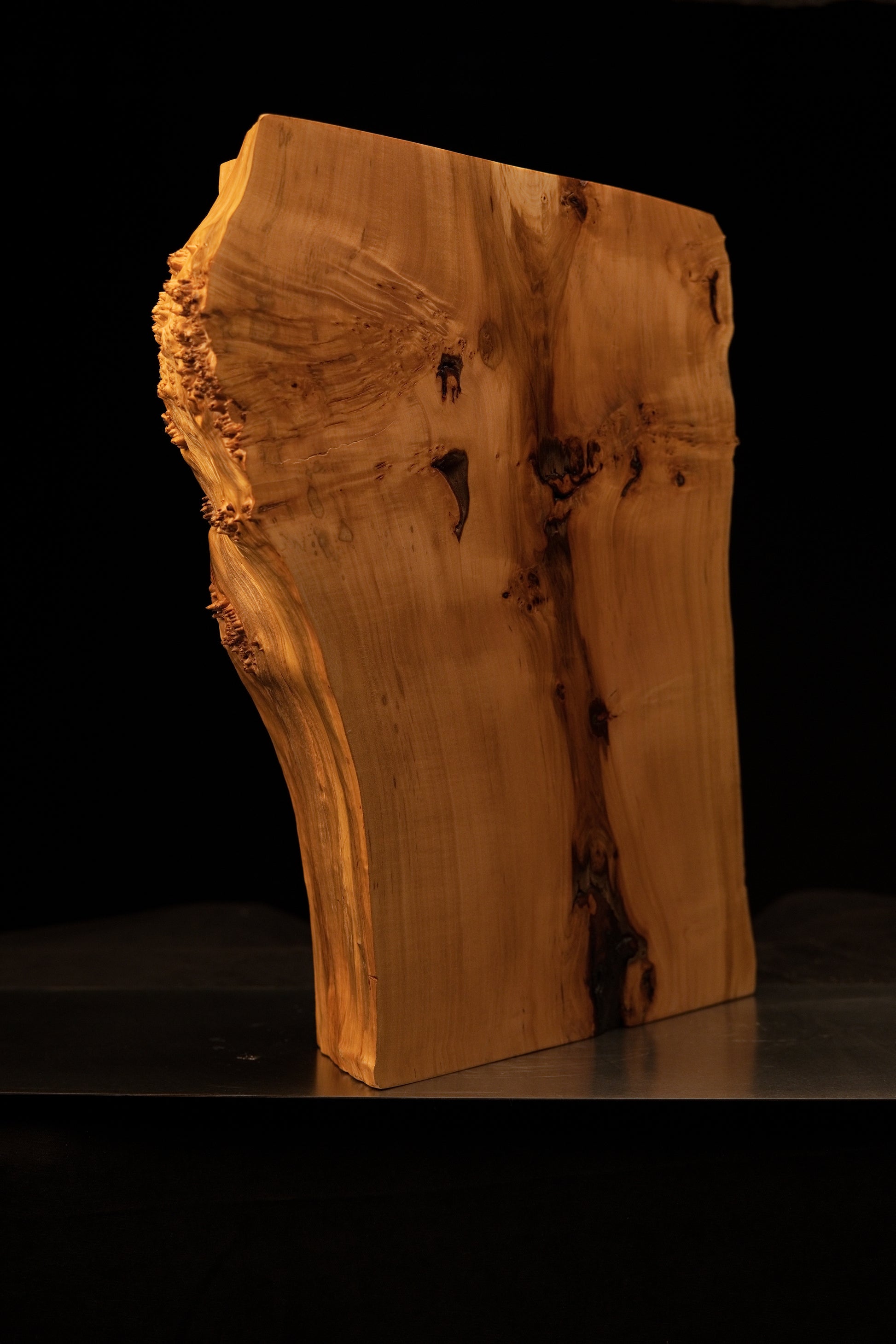 Angled profile of a climate-stable architectural timber element revealing smooth vertical grain and wavy organic burl textures.   