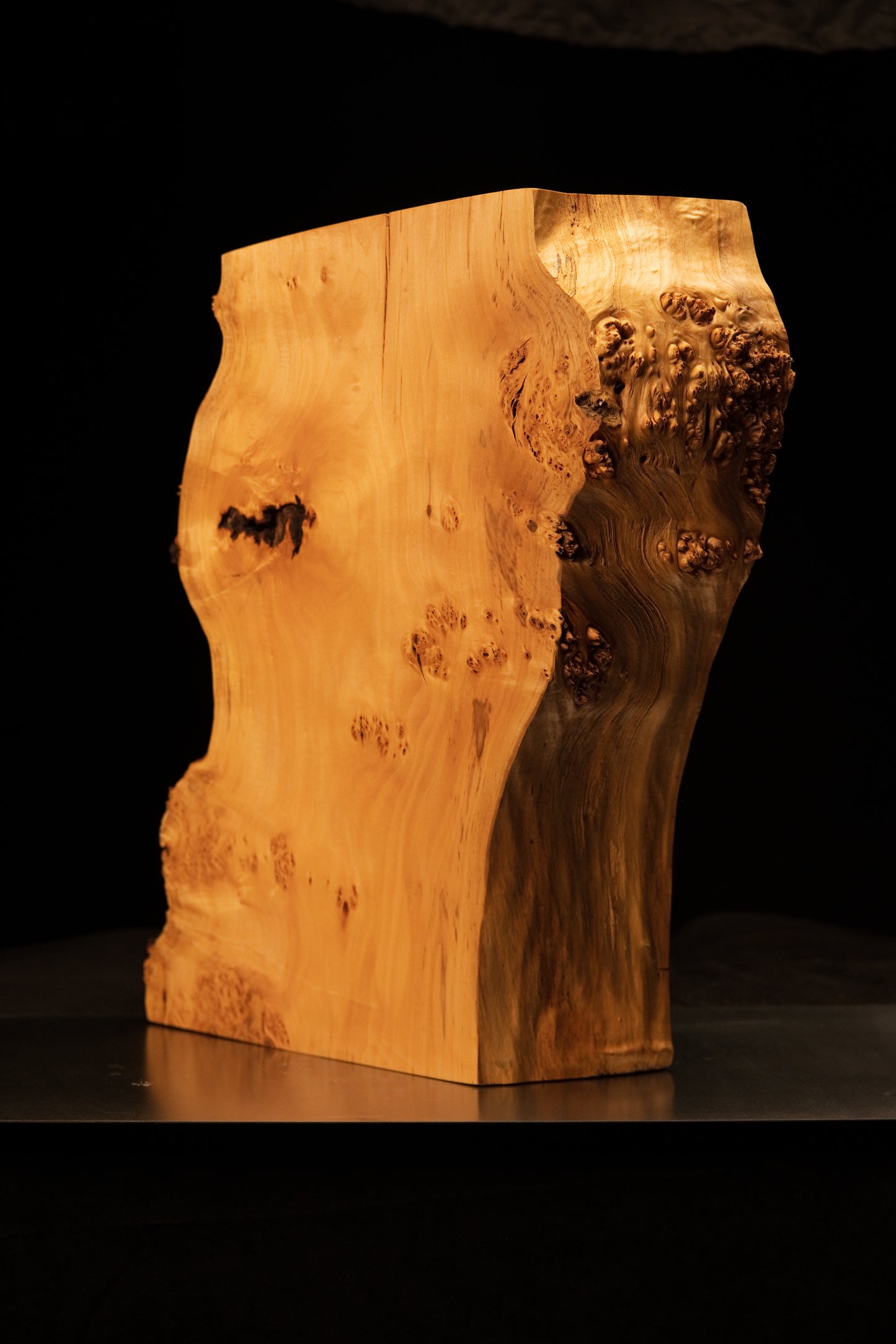 Side perspective of an epoxy-free structural wooden block highlighting a flat precision cut face alongside a dense burl profile.   