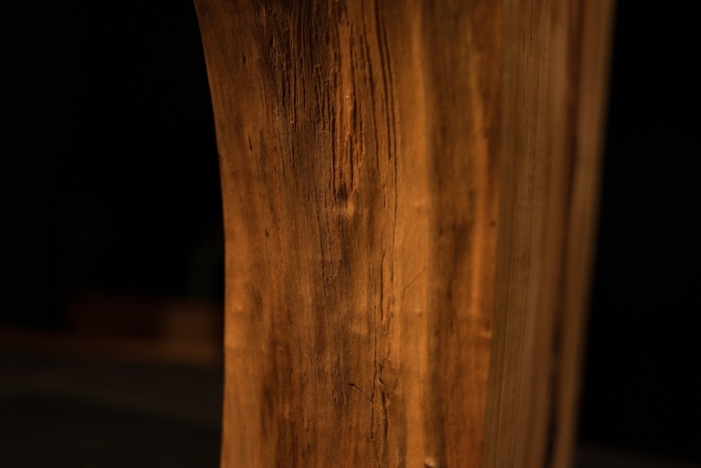 Close detail of the perfectly flat polished face on a biophilic architectural wood block displaying sweeping vertical golden grain.   