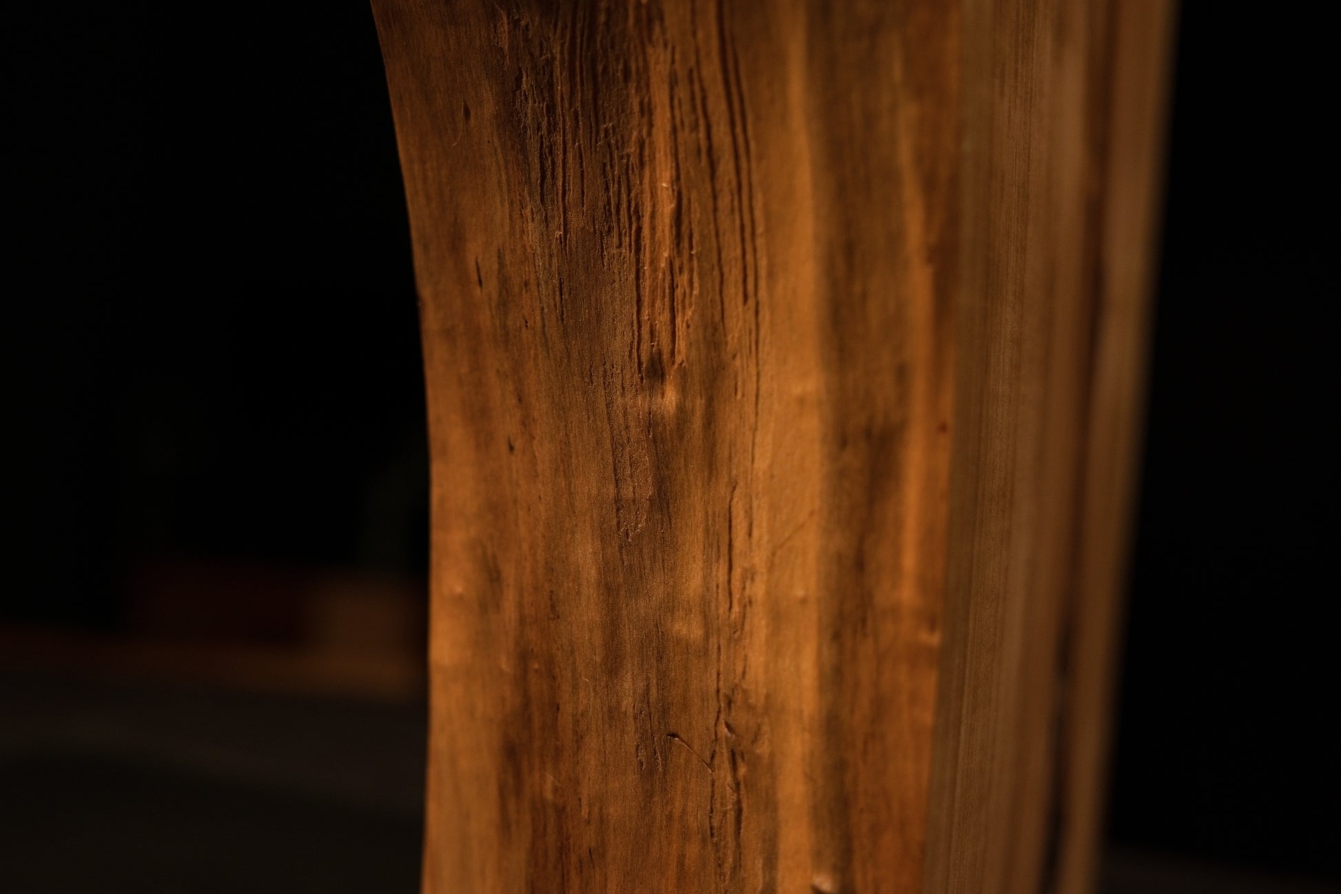 Close detail of the perfectly flat polished face on a biophilic architectural wood block displaying sweeping vertical golden grain.   