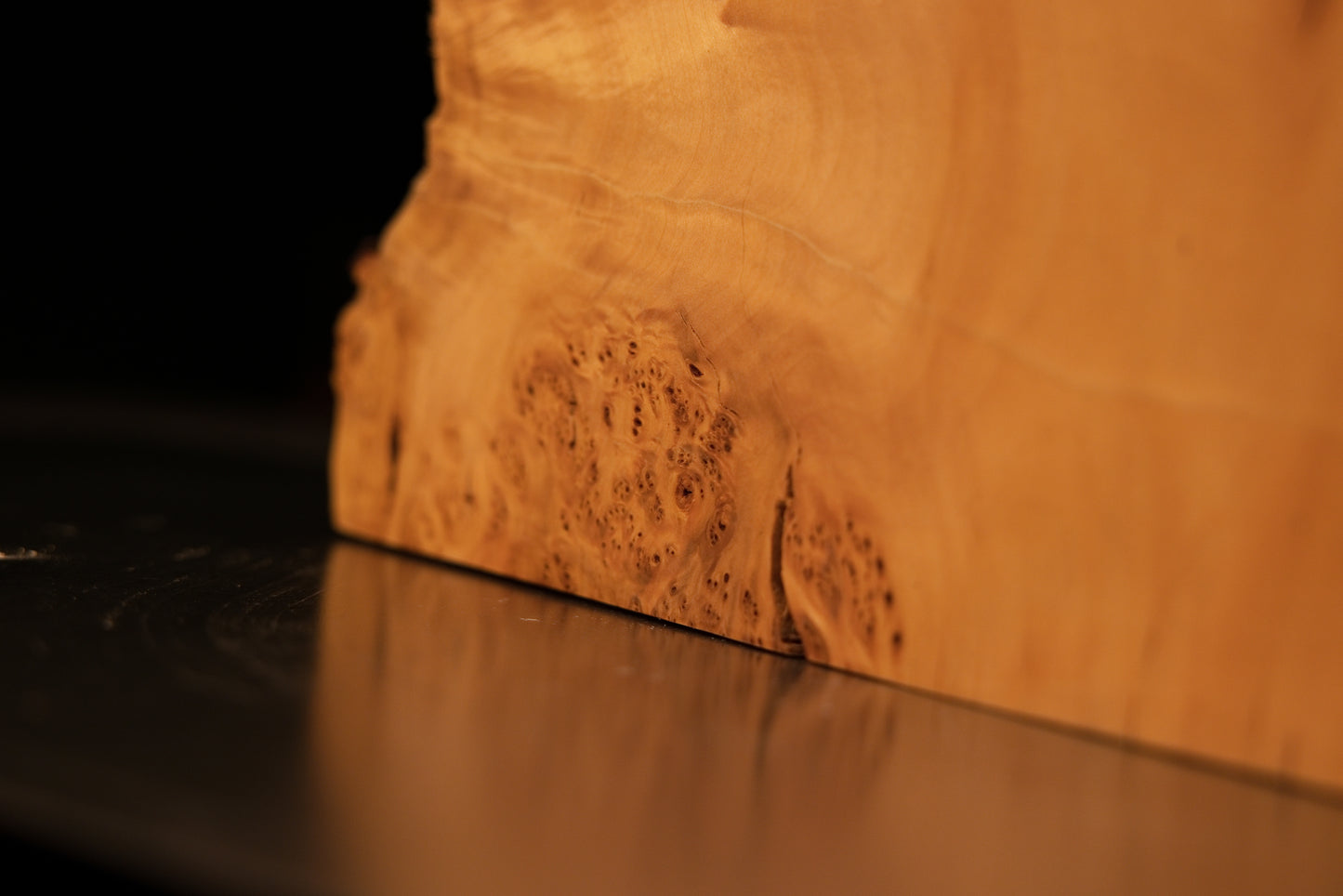 Lower base corner of an epoxy-free architectural slab showcasing a highly textured burl edge resting flat on a structural surface.   