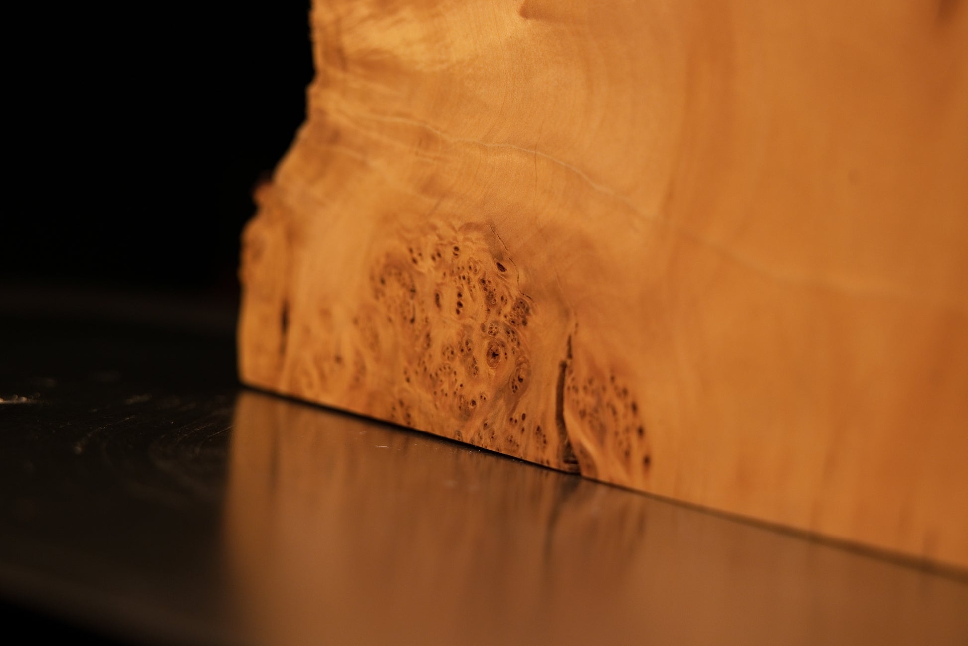 Lower base corner of an epoxy-free architectural slab showcasing a highly textured burl edge resting flat on a structural surface.   