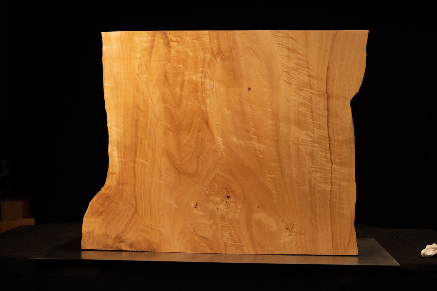 Front perspective of a climate-stable architectural wood block displaying a smooth golden face and wavy side botanical edges.    