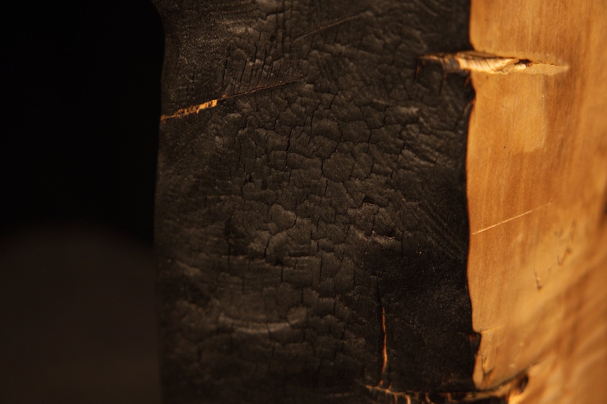 Top corner perspective highlighting a flat precision cut intersecting the dark charred edge of an epoxy-free structural block.    