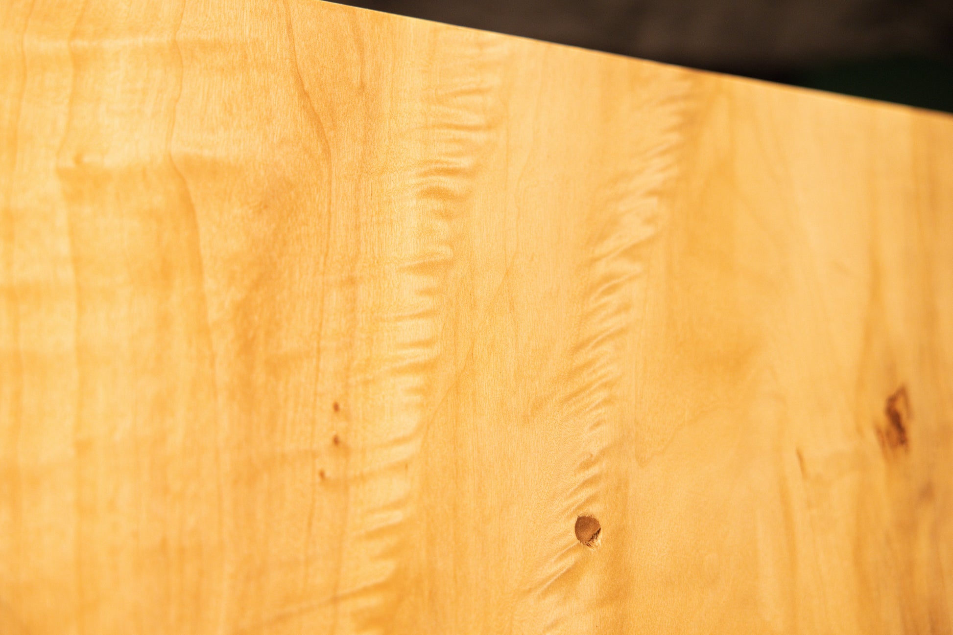 Detailed macro of sweeping golden vertical wood grain lines on the polished face of a floor-heating compatible centerpiece.    