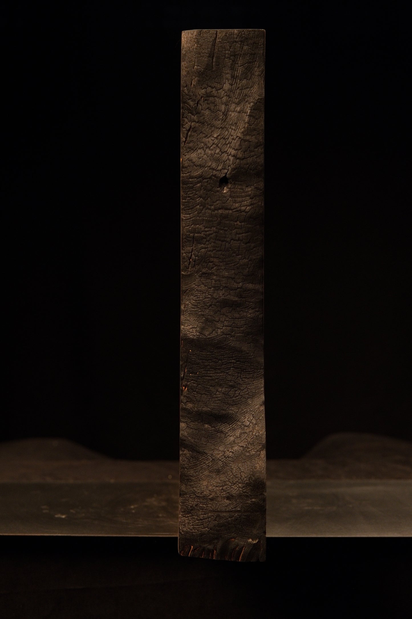 Straight vertical profile of the dark heavily textured charred face on a biophilic commercial wooden structural centerpiece.    