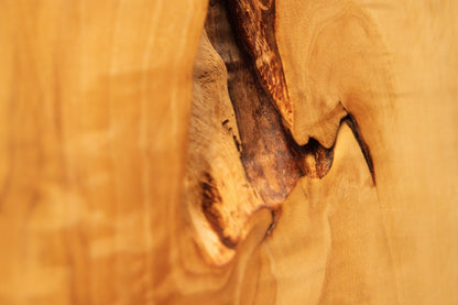 Macro perspective of a jagged dark structural void embedded in the polished flat surface of a climate-stable timber element.    