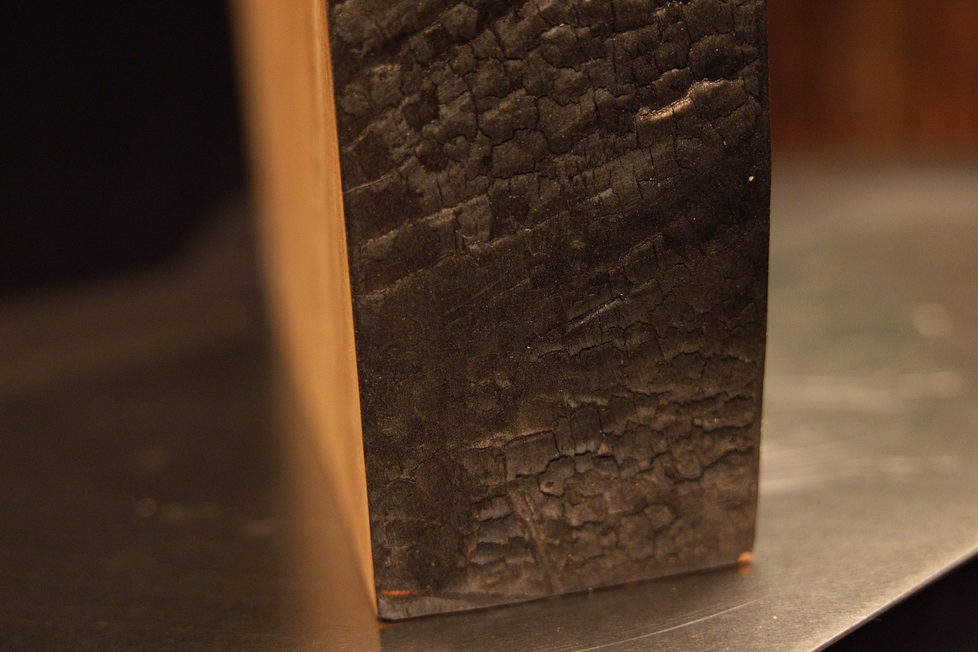 Extreme macro of a heavily textured dark side edge contrasting with a smooth horizontal top cut on a biophilic wood monolith.[cite: 3, 4]
