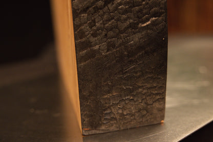 Extreme macro of a heavily textured dark side edge contrasting with a smooth horizontal top cut on a biophilic wood monolith.[cite: 3, 4]