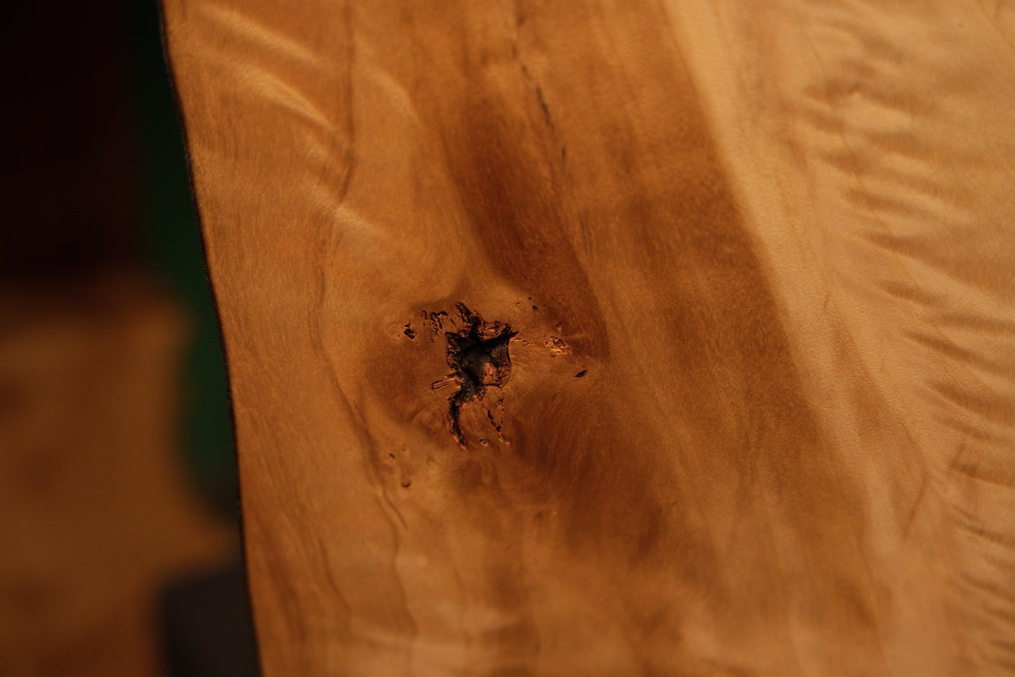 Macro detail of a jagged dark central knot embedded in the smooth polished surface of an interior architectural wood slab.[cite: 3, 4]