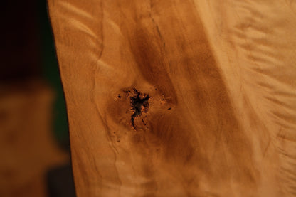 Macro detail of a jagged dark central knot embedded in the smooth polished surface of an interior architectural wood slab.[cite: 3, 4]