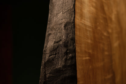 Lower corner macro where a deeply charred structural edge meets the flawlessly flat precision cut base of a timber centerpiece.  