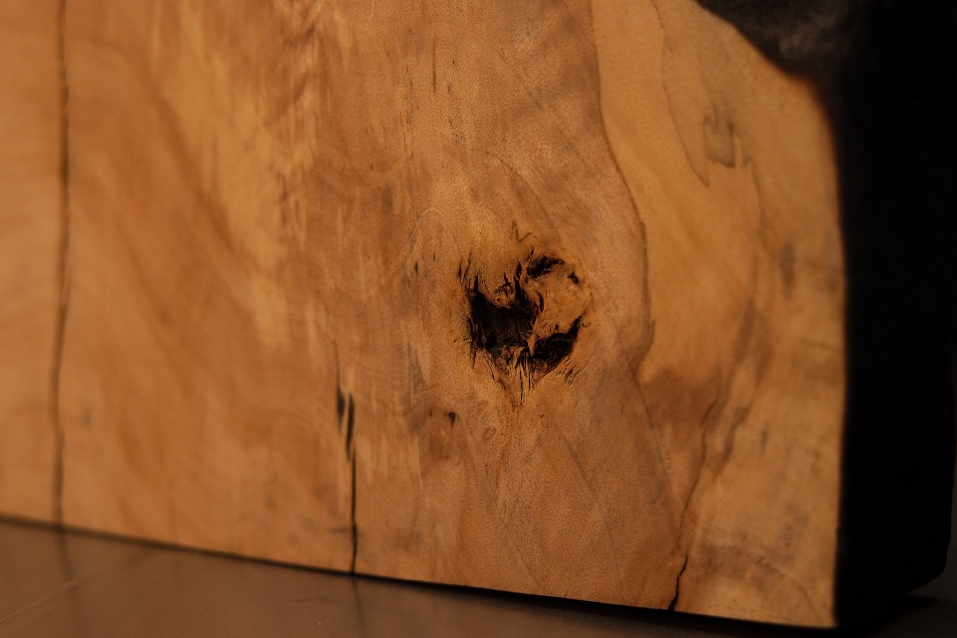 Detailed view of the smooth polished face on an architectural wooden slab displaying sweeping grain and dark biological inclusions. 