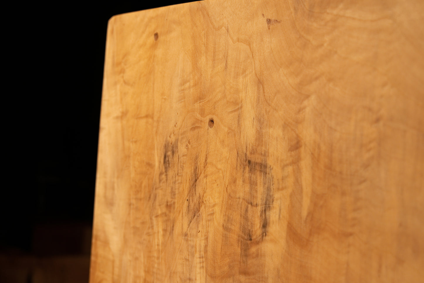 Detailed macro of natural biological pigmentations interrupting the smooth vertical wood grain on an architectural interior element. 