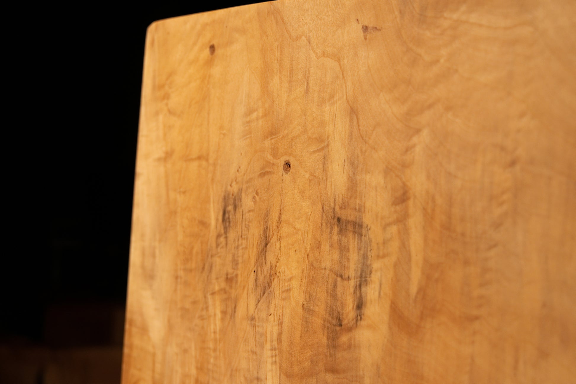 Detailed macro of natural biological pigmentations interrupting the smooth vertical wood grain on an architectural interior element. 