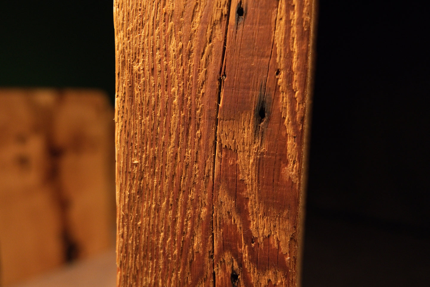 Angled macro showcasing deep historic tool scars and sweeping golden grain lines on a fully stabilized structural wooden element. 