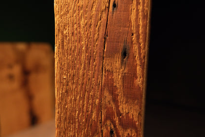 Angled macro showcasing deep historic tool scars and sweeping golden grain lines on a fully stabilized structural wooden element. 