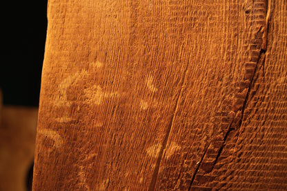 Extreme macro of deep golden grain lines curving gently around a historical surface defect on a museum-quality biophilic timber. 