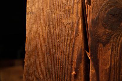 Macro focus on extremely dense vertical wood fibers and a dark biological knot on a floor-heating compatible structural log. 