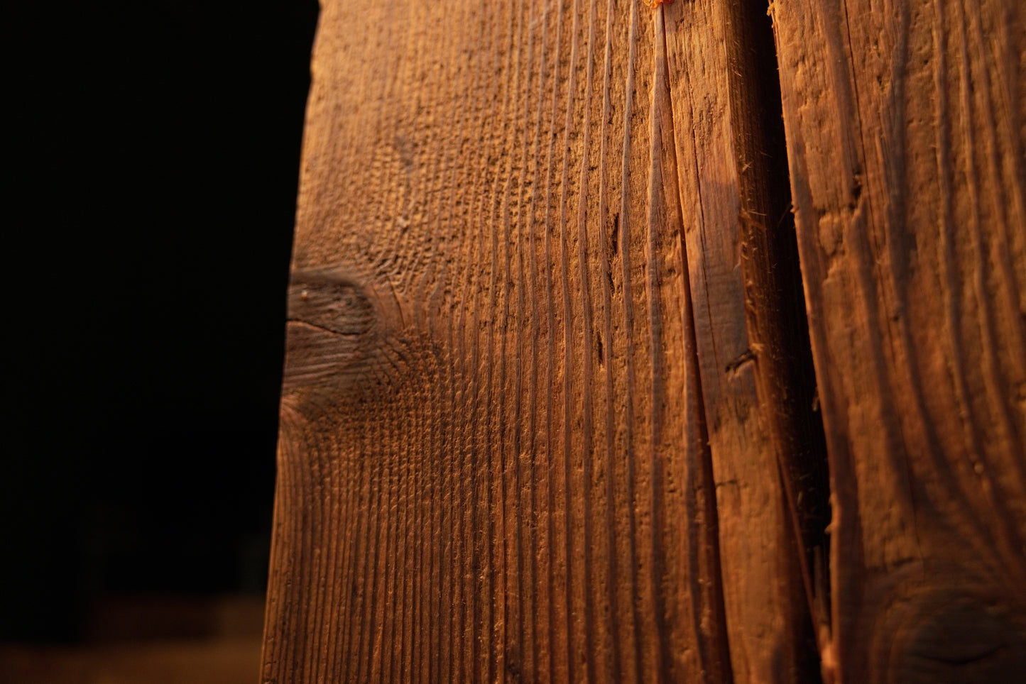 Detailed macro showing sweeping golden grain curving dynamically around an authentic dark knot on an interior wood piece. 