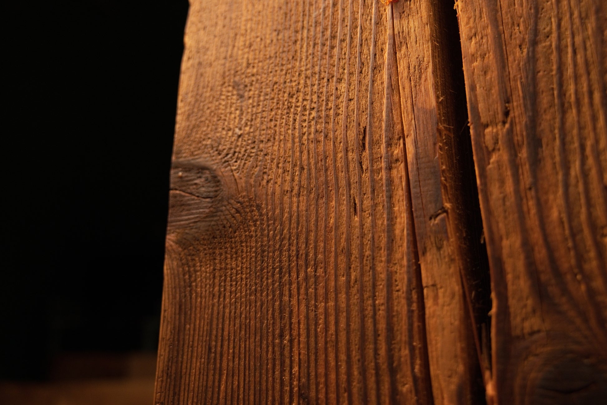 Detailed macro showing sweeping golden grain curving dynamically around an authentic dark knot on an interior wood piece. 