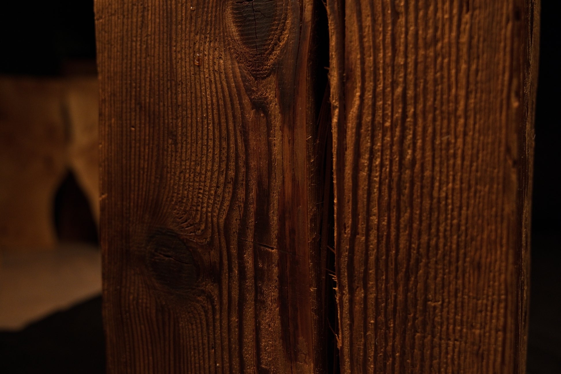 Extreme macro of a dark vertical crack embedded between tight golden grain lines on a fully stabilized architectural beam. 