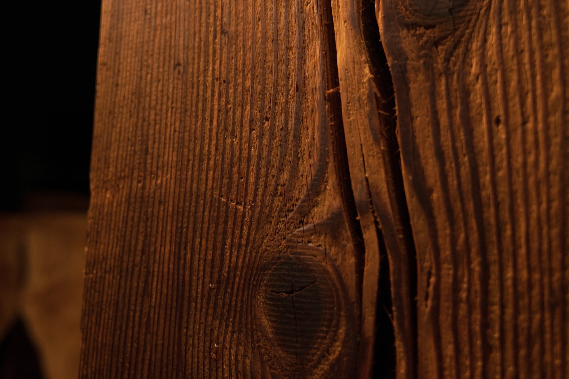 Close-up of wood grain curving gracefully around a deep vertical split in the face of a climate-stable commercial timber. 