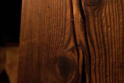 Close-up of wood grain curving gracefully around a deep vertical split in the face of a climate-stable commercial timber. 