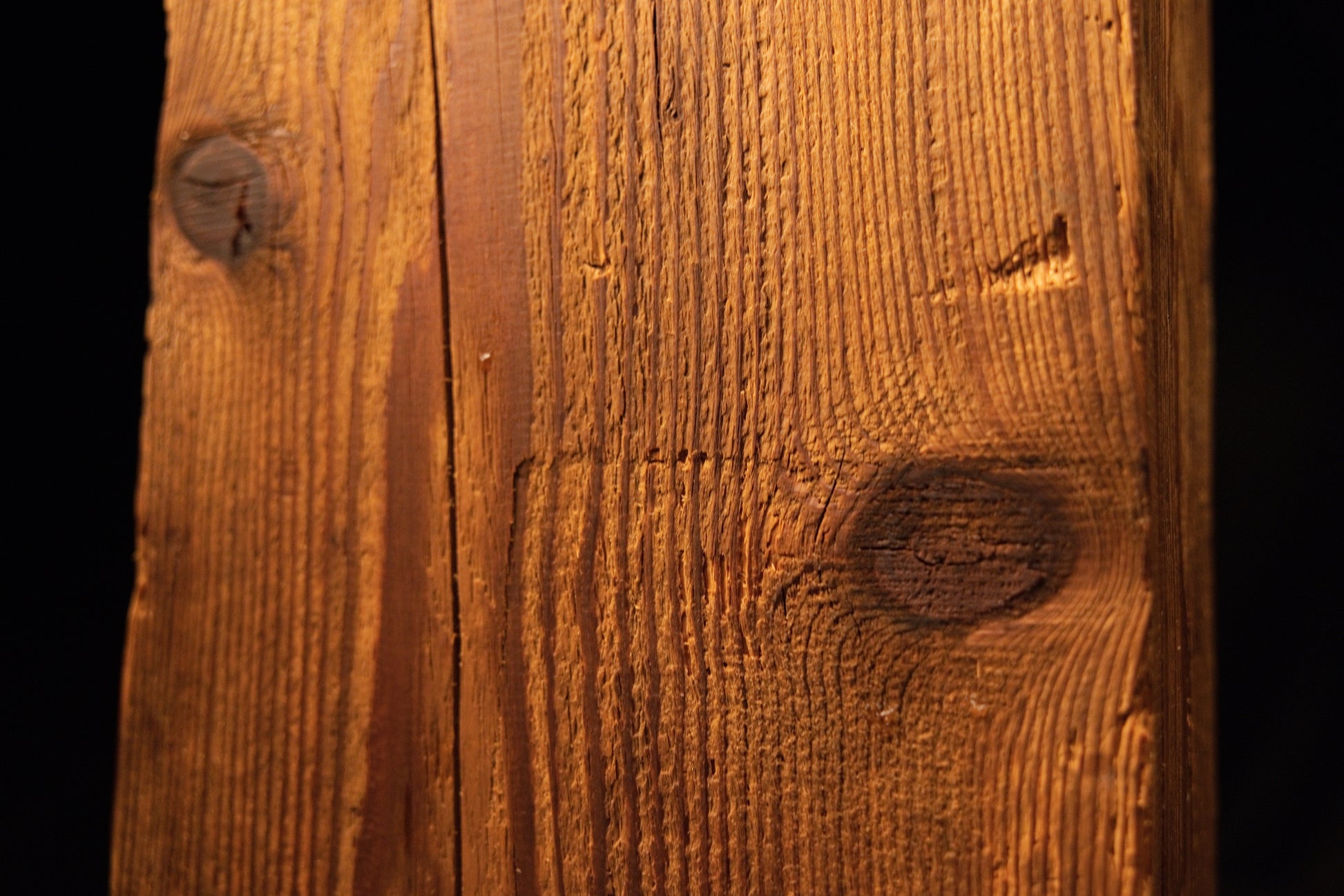 Close perspective highlighting a dark organic knot embedded within the sweeping side grain of an investment-grade beam. 