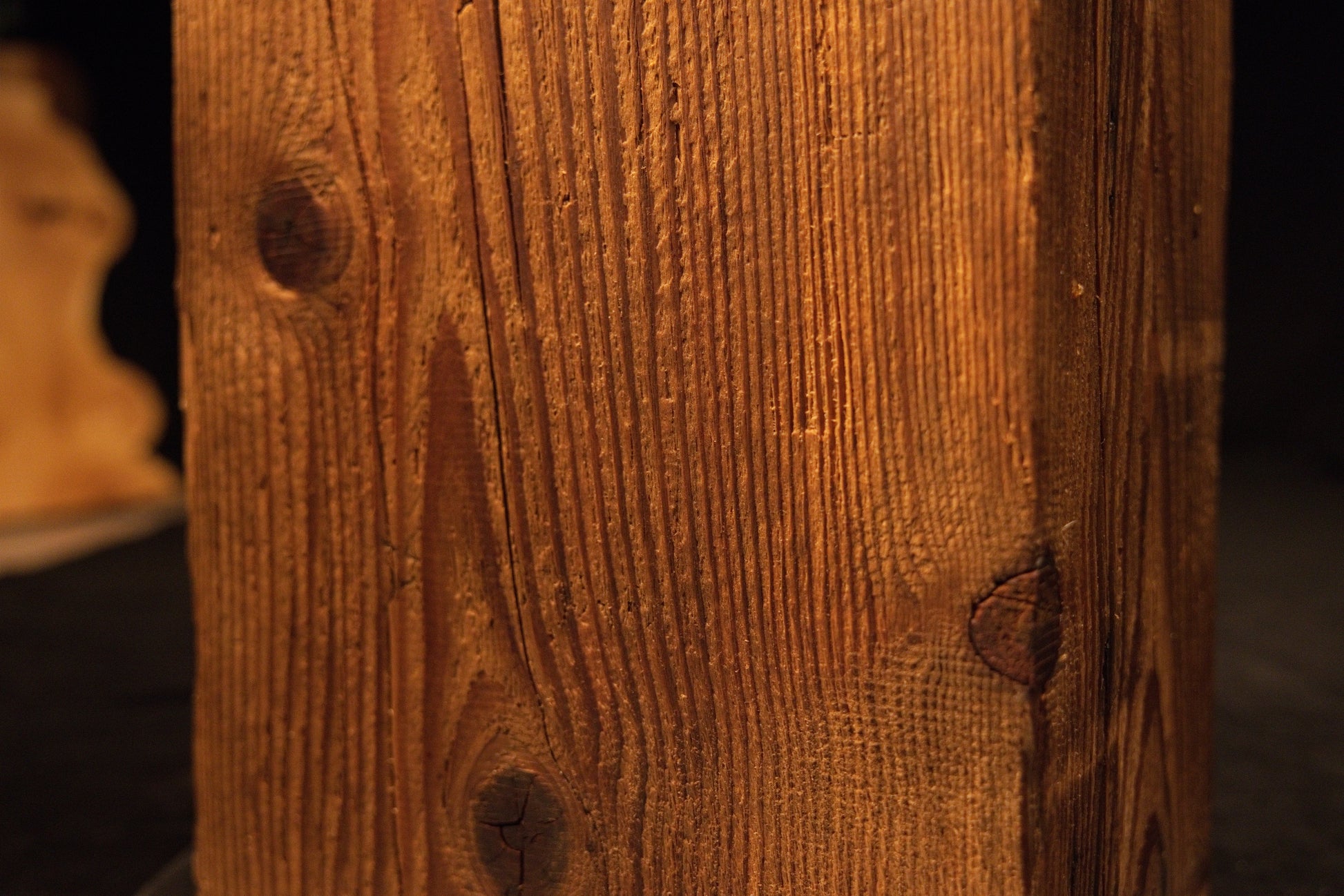 Extreme macro capturing sweeping vertical grain lines curving around a small dark knot on a climate-stable timber piece. 