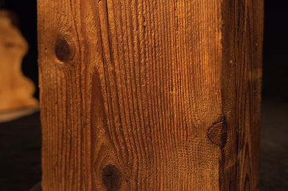 Extreme macro capturing sweeping vertical grain lines curving around a small dark knot on a climate-stable timber piece. 