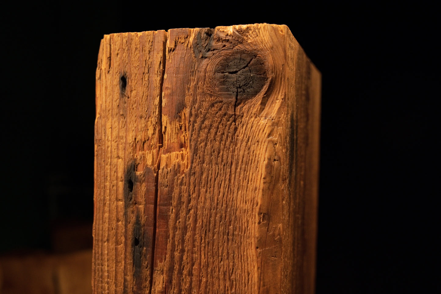 Detailed macro showing sweeping golden grain curving dynamically around an authentic dark knot on an interior wood piece.  