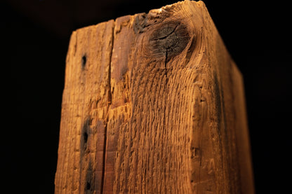 Extreme macro of a dark vertical crack embedded between tight golden grain lines on a fully stabilized architectural beam.  