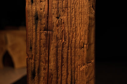 Close detail of a dark biological knot intersecting the sharp vertical corner edge of an epoxy-free structural wooden slab.  