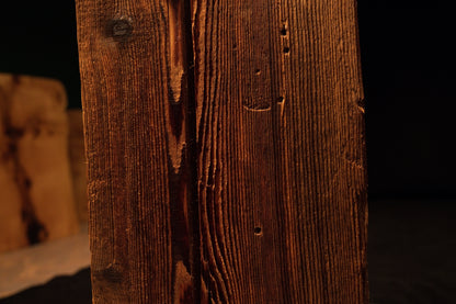 Extreme macro capturing sweeping vertical grain lines curving around a small dark knot on a climate-stable timber piece.  