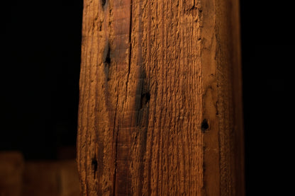 Angled macro showcasing deep historic tool scars and sweeping golden grain lines on a fully stabilized structural wooden element.  