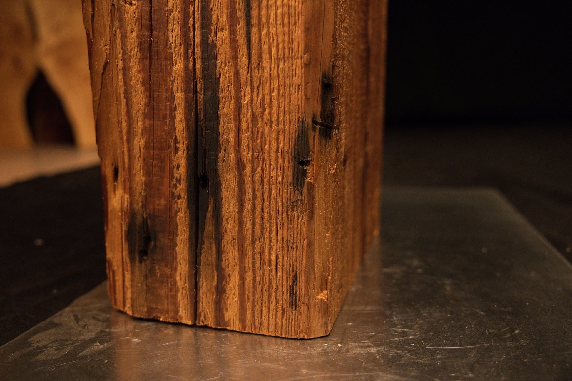 Extreme macro of deep golden grain lines curving gently around a historical surface defect on a museum-quality biophilic timber.  