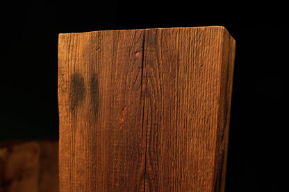 Extreme macro of a prominent dark knot located beside a deep vertical fissure on a climate-stable architectural timber block.  