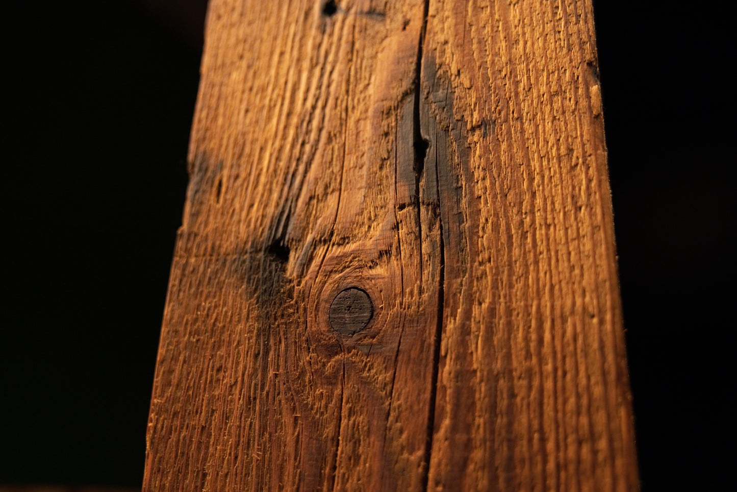 Macro focus highlighting a deep biological knot intersecting a long vertical crack on an epoxy-free commercial interior beam.  