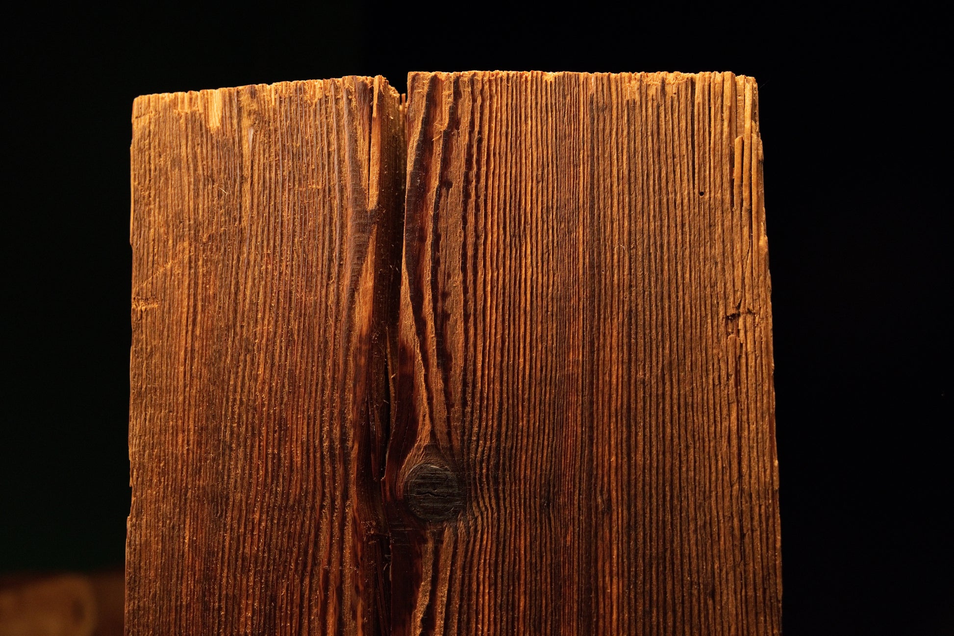 Detailed perspective of a deep vertical split revealing dark internal textures within a highly stabilized biophilic wood piece.  