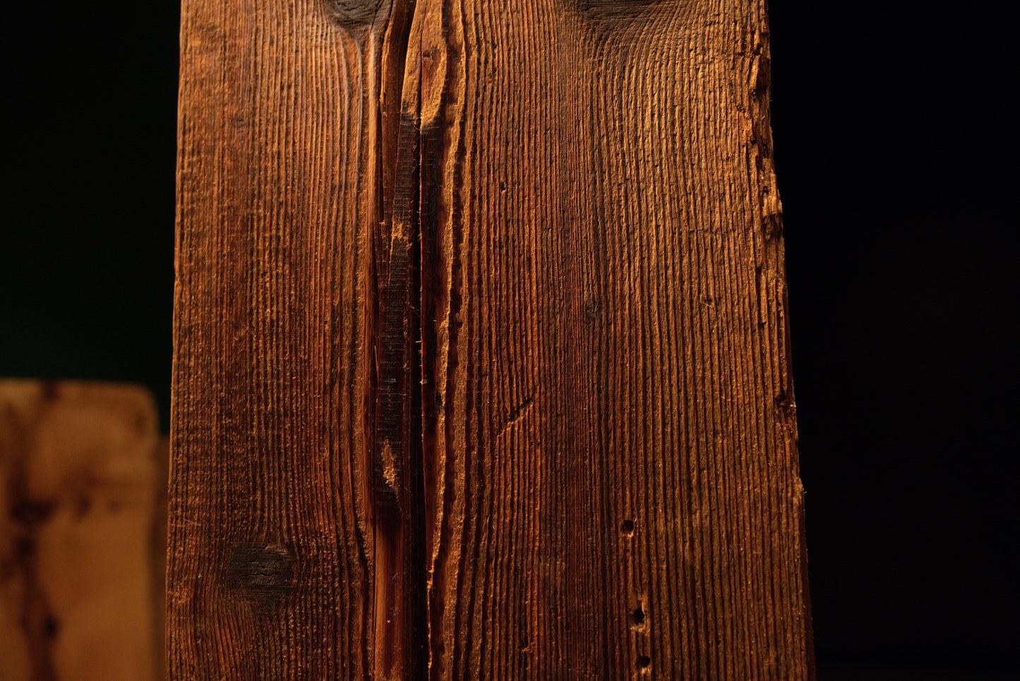 Macro view of a jagged natural fissure casting dark shadows across the deeply furrowed face of a climate-stable timber block.  