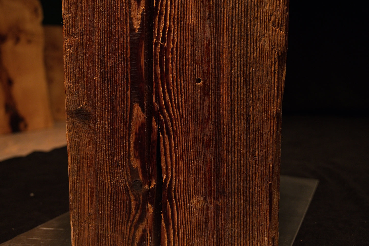 Close-up of the lower corner where tight vertical wood fibers meet a perfectly flat precision cut on a floor-heating safe log.  