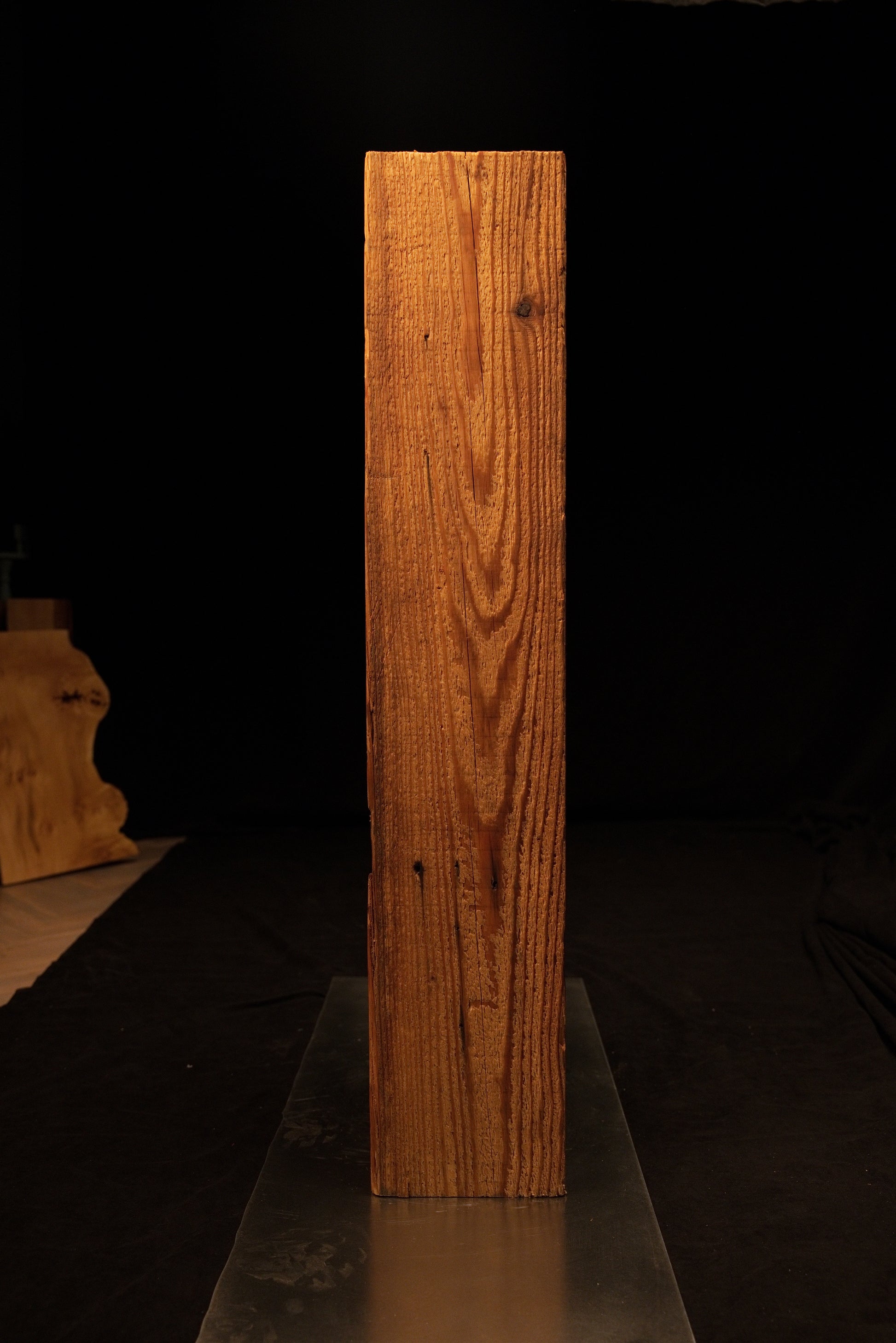 Full vertical view of a tall climate-stable structural timber beam displaying tight vertical grain and scattered nail holes. 