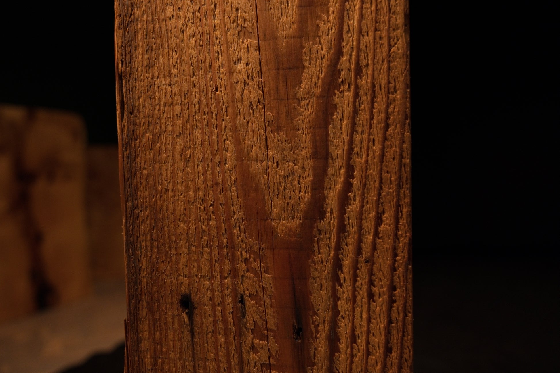 Detailed macro showing sweeping golden grain curving dynamically around a tiny dark blemish on an interior wood surface. 